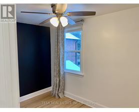 A room with a ceiling fan and a window showing a view of a building outside.