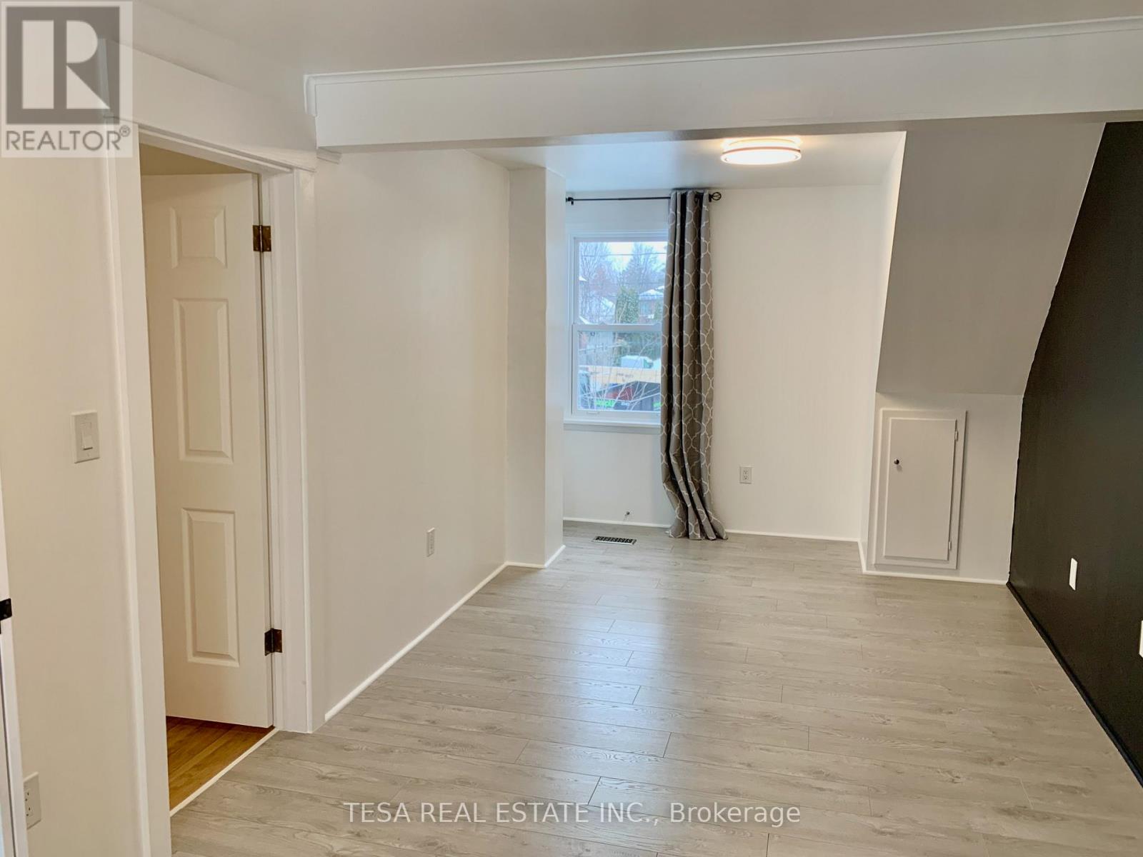 A spacious room with a window and a door on the left side.