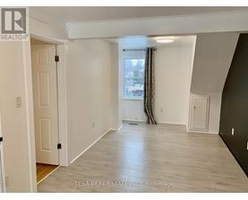 A spacious room with a window and a door on the left side.