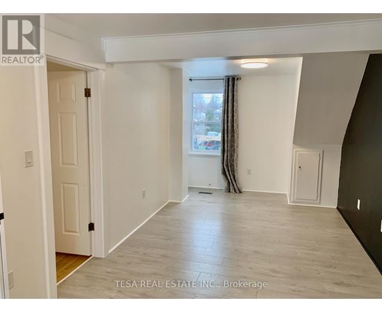 A spacious room with a window and a door on the left side.