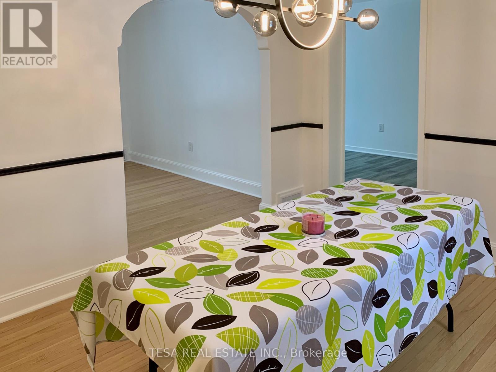 A bedroom with a bed covered in a leaf-patterned bedspread.
