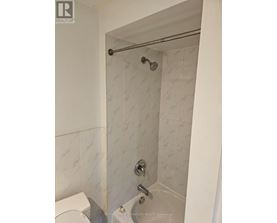 A white tiled shower with a glass door and a silver shower head.