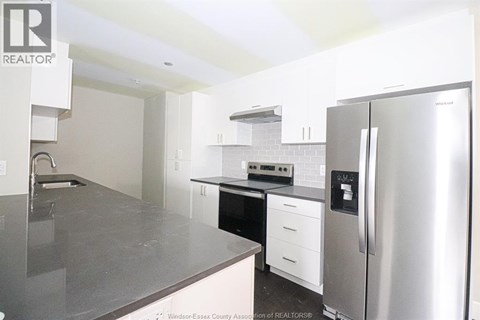 A kitchen with a refrigerator, sink, and cabinets.