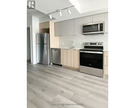 A modern kitchen with a refrigerator, oven, and microwave.
