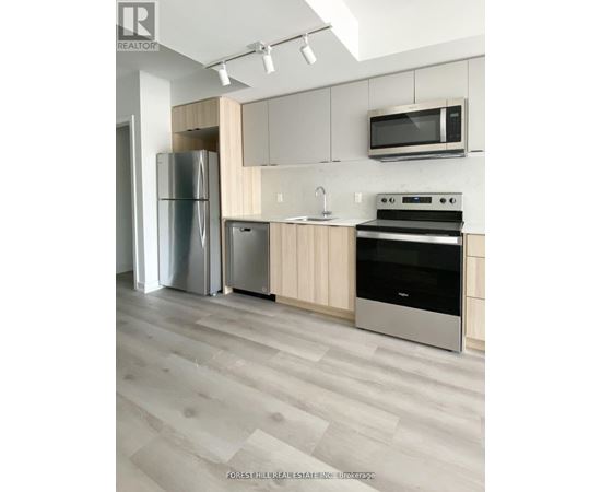A modern kitchen with a refrigerator, oven, and microwave.