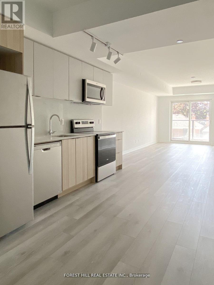 A kitchen with a refrigerator, microwave, and oven.
