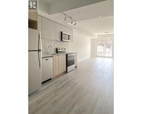 A kitchen with a refrigerator, microwave, and oven.