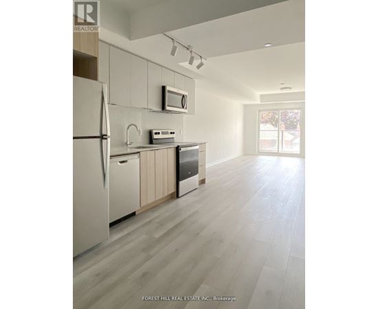 A kitchen with a refrigerator, microwave, and oven.