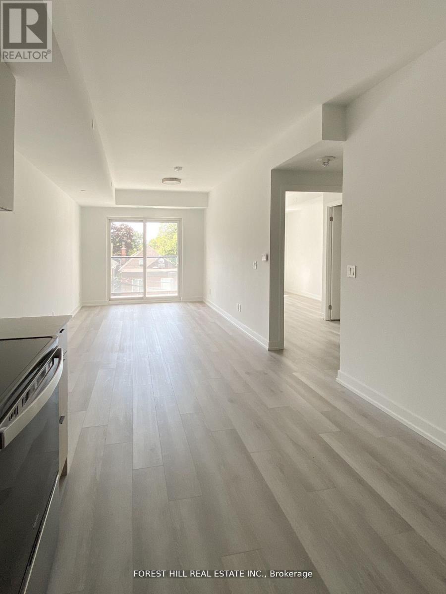 A kitchen with a dishwasher and a wooden floor leading to a hallway.