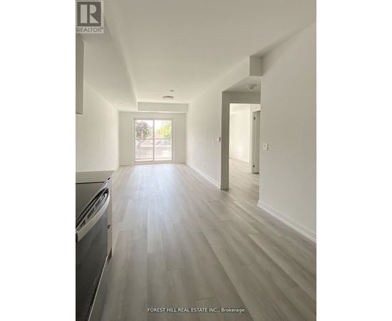 A kitchen with a dishwasher and a wooden floor leading to a hallway.
