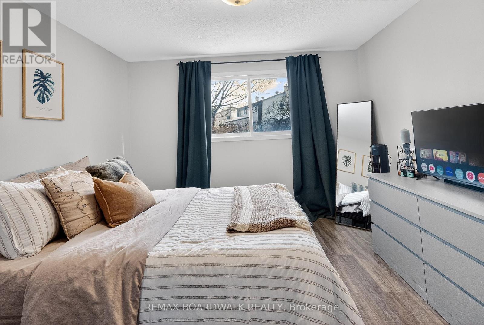 A bedroom with a large bed and a window with curtains.