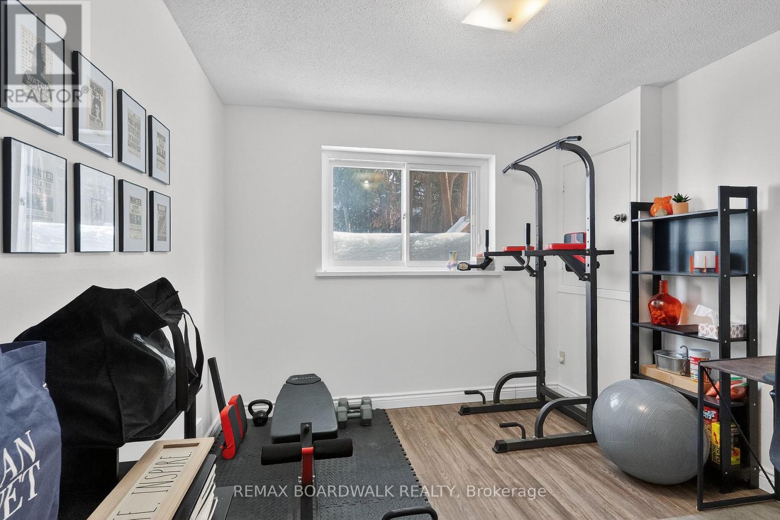 A gym room with a bench, weights, and a window.