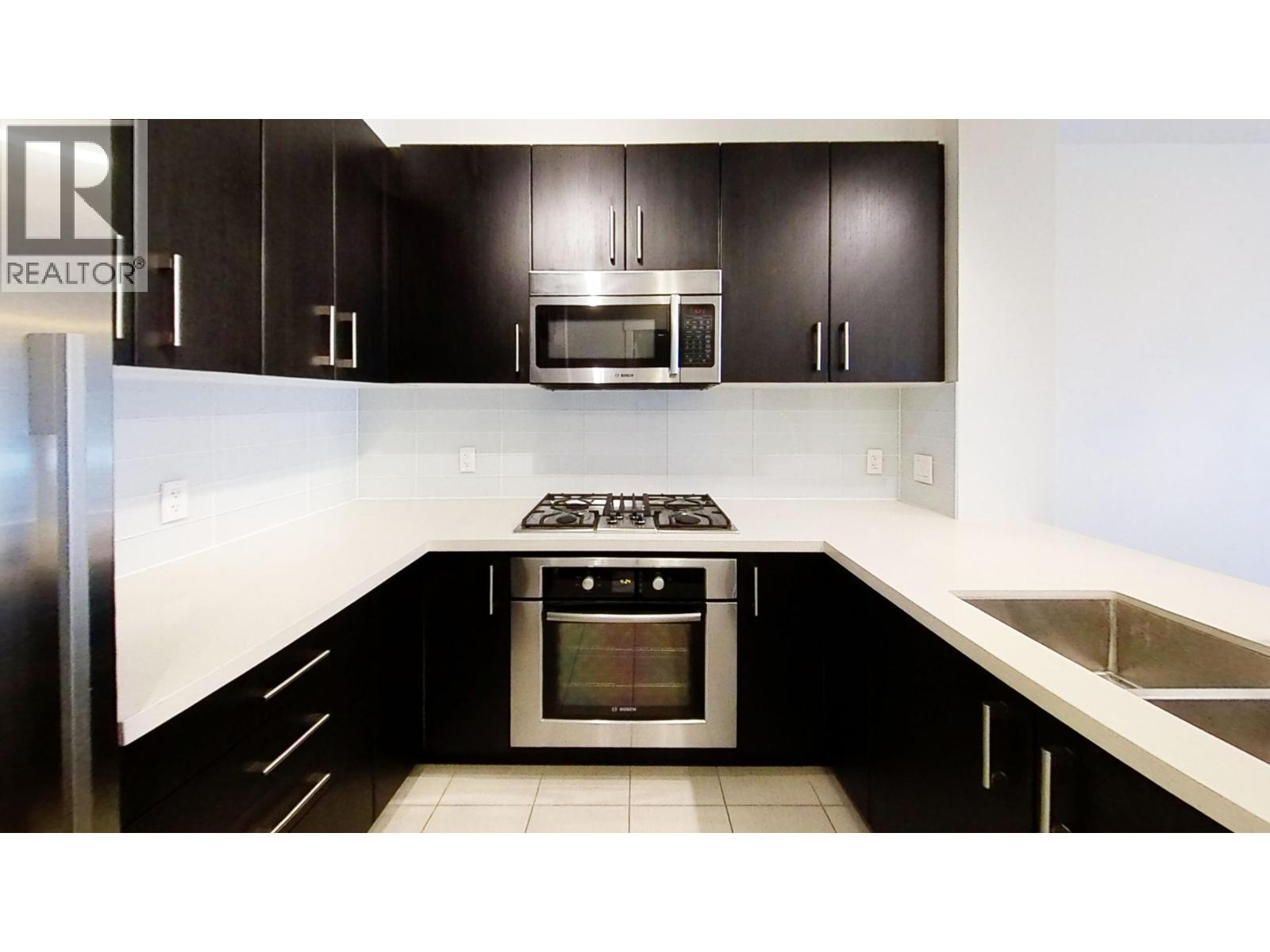 A modern kitchen with black cabinets and stainless steel appliances.