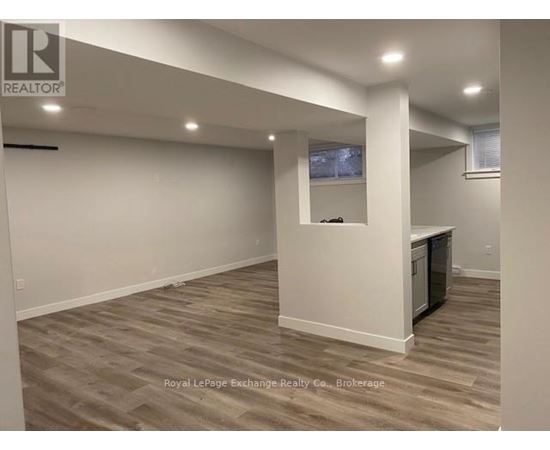 A spacious room with wooden flooring and a television mounted on the wall.