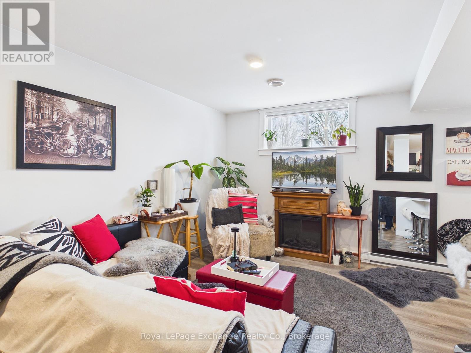 A living room with a couch, a fireplace, and a painting on the wall.