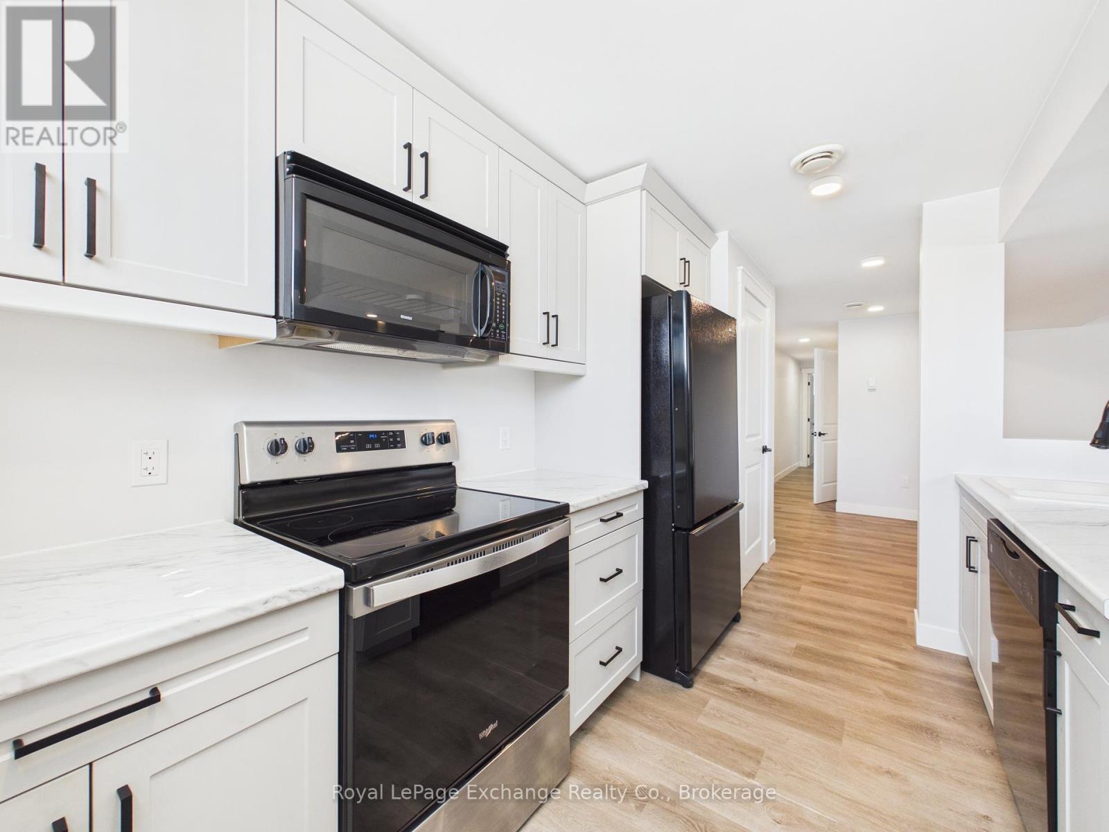 A kitchen with white cabinets and a white island with bar stools.