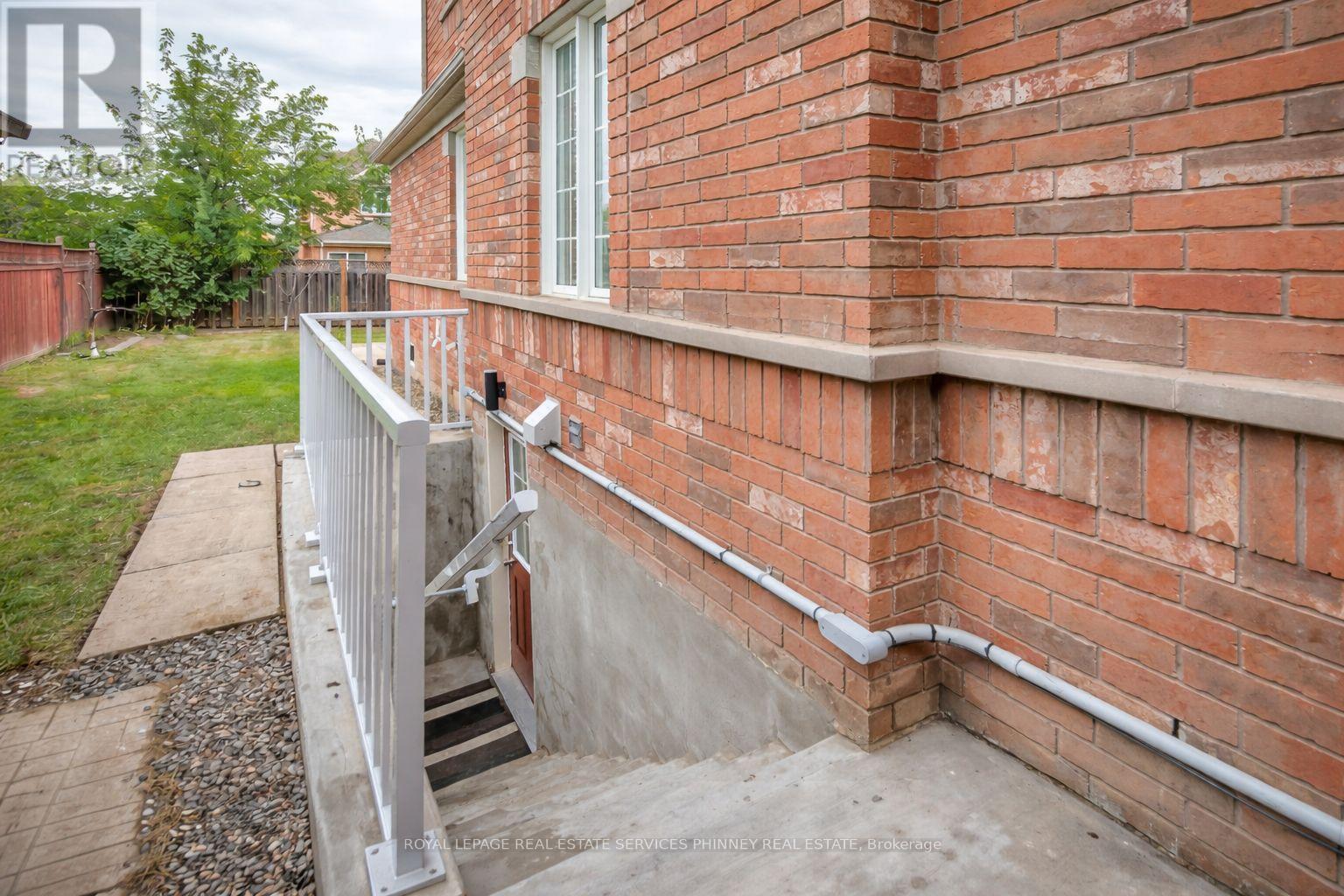 A red brick house with a white railing and steps leading to a door.