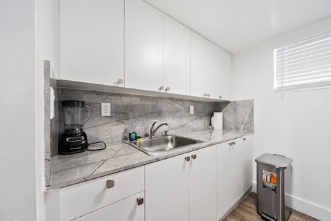 A kitchen with white cabinets and a marble countertop.