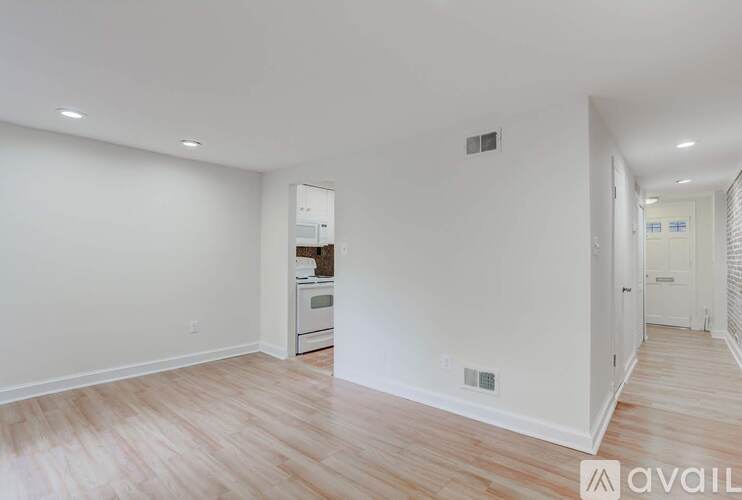 A spacious room with a kitchen area and wooden flooring.