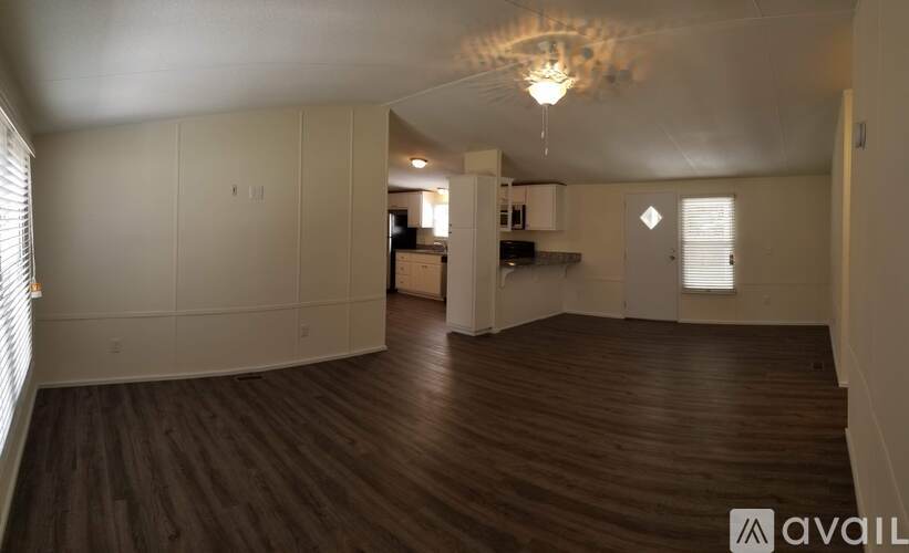 A spacious room with wooden floors and a chandelier hanging from the ceiling.