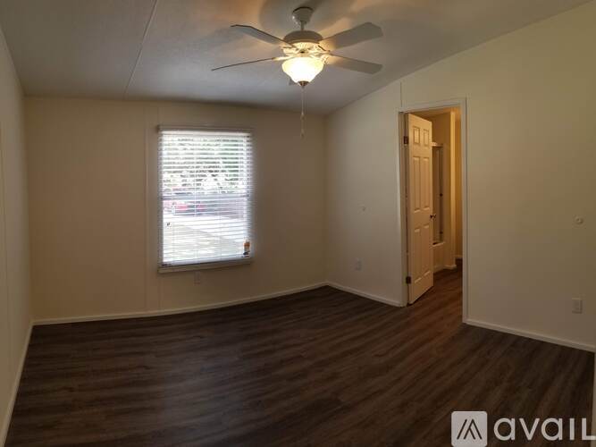 A room with a ceiling fan and wooden flooring.