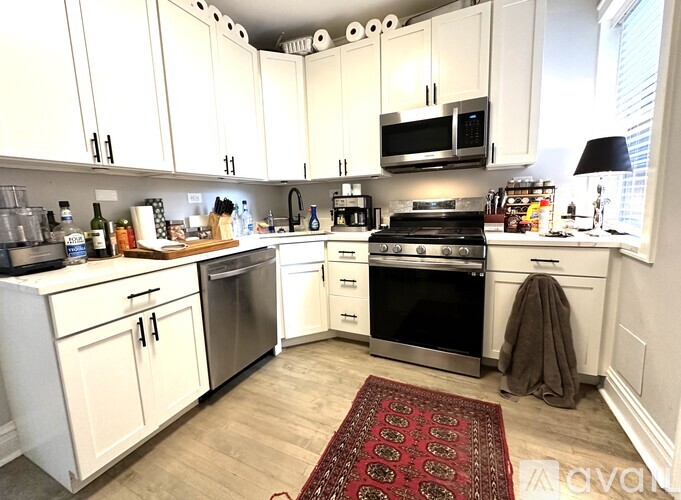 A kitchen with white cabinets and a red rug on the floor.