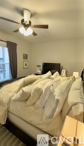 A bedroom with a bed covered in white sheets and pillows.