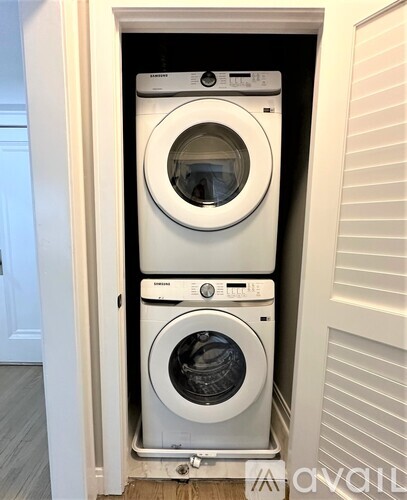 A white washing machine is stacked on top of another white washing machine in a small space.