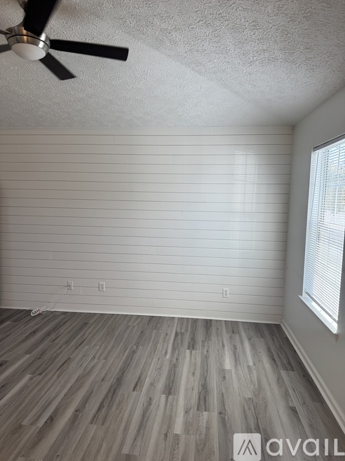 A room with a ceiling fan and wooden flooring.