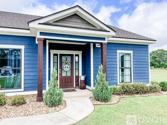 A blue house with a brown door and a sign that says "For Sale".