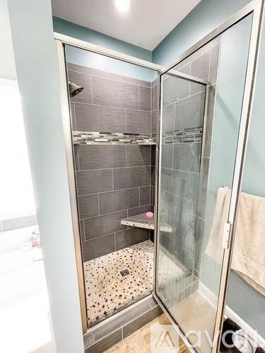A shower with a glass door and a tiled wall.