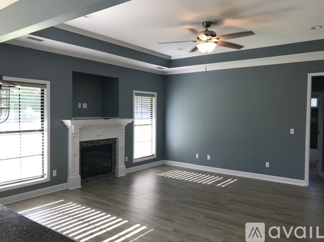 A spacious living room with a fireplace and a ceiling fan.