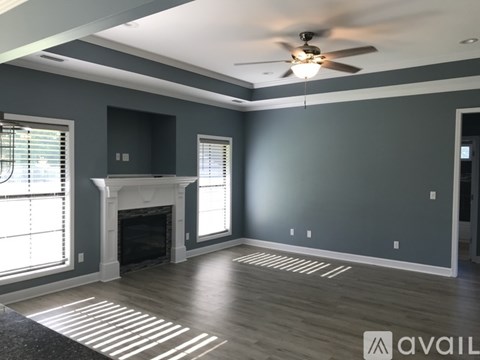 A spacious living room with a fireplace and a ceiling fan.