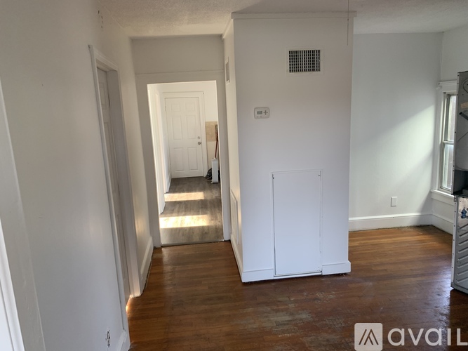 A room with white walls and wooden floors is available for rent.