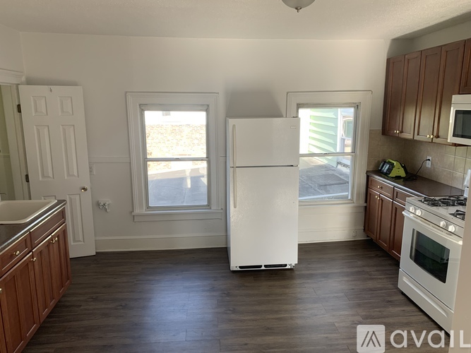 A kitchen with a white refrigerator, wooden cabinets, and a window.