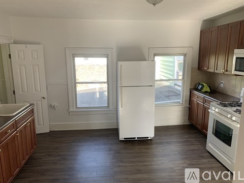 A kitchen with a white refrigerator, wooden cabinets, and a window.