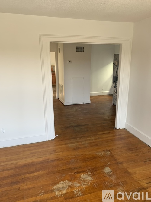 A room with a white door and wooden floor.