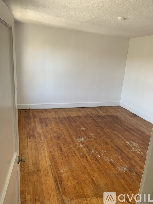 A room with wooden flooring and a white door.