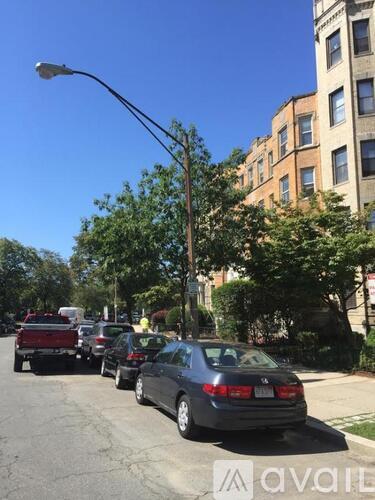 Cars parked on a street with a building in the background.