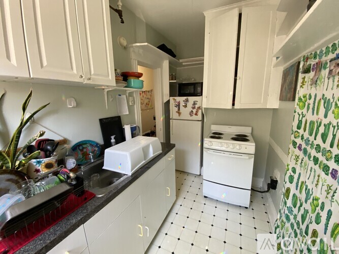 A kitchen with white cabinets and a black and white checkered floor.
