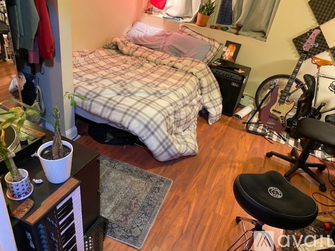 A room with a bed, a guitar, a chair, and a plant.
