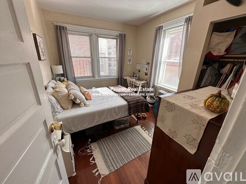A bedroom with a bed, a desk, and a window.
