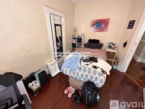A bedroom with a bed, chair, and a painting on the wall.