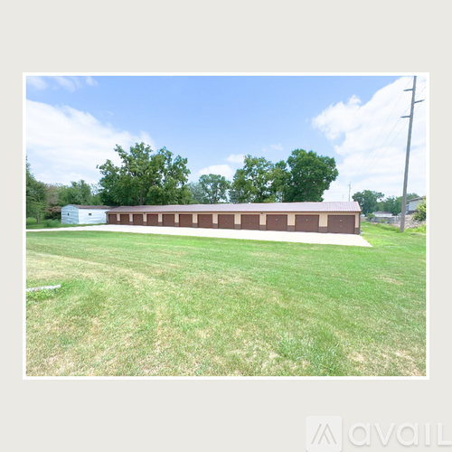 A long building with a brown roof is surrounded by a grassy field.