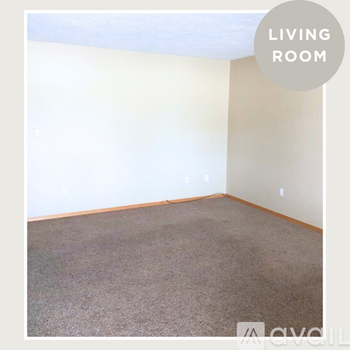 A living room with a carpeted floor and white walls.