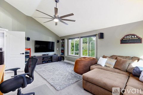 A living room with a brown couch and a ceiling fan.