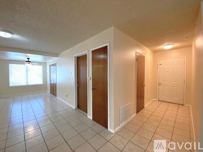 A spacious room with tiled flooring and three doors.