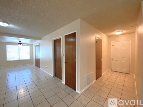 A spacious room with tiled flooring and three doors.