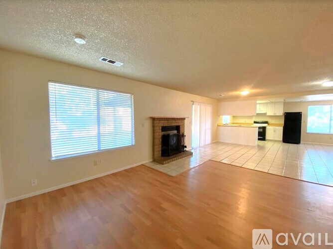 A spacious living room with a fireplace and a kitchen area in the background.