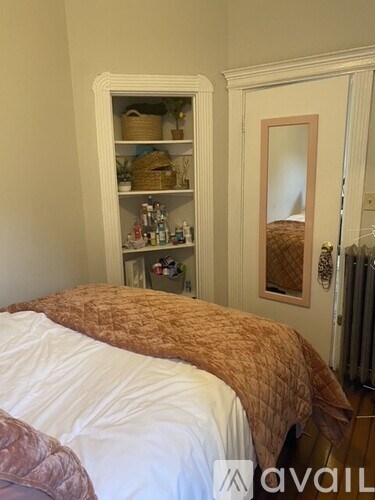 A bedroom with a bed and a shelf with various items on it.